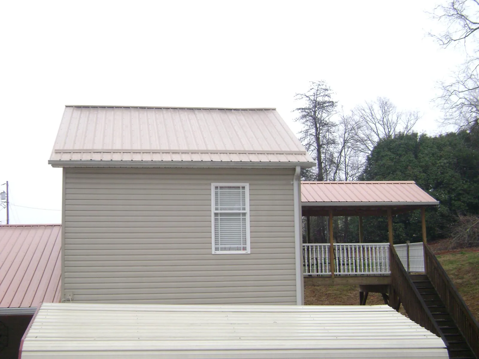 Tan metal roofs on a two story addition and attached porch, from a Roof Replacement job in Dearborn