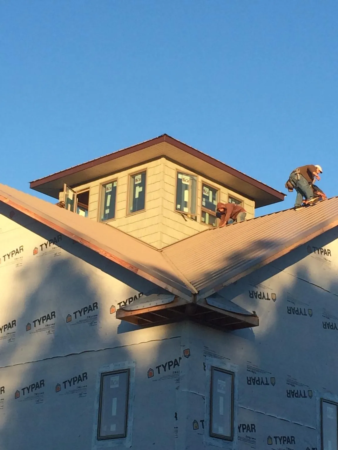 Roofers working around a rooftop cupola on a new metal roof at sunset — Roof Waterproofing in Dearborn by Roofing Brothers